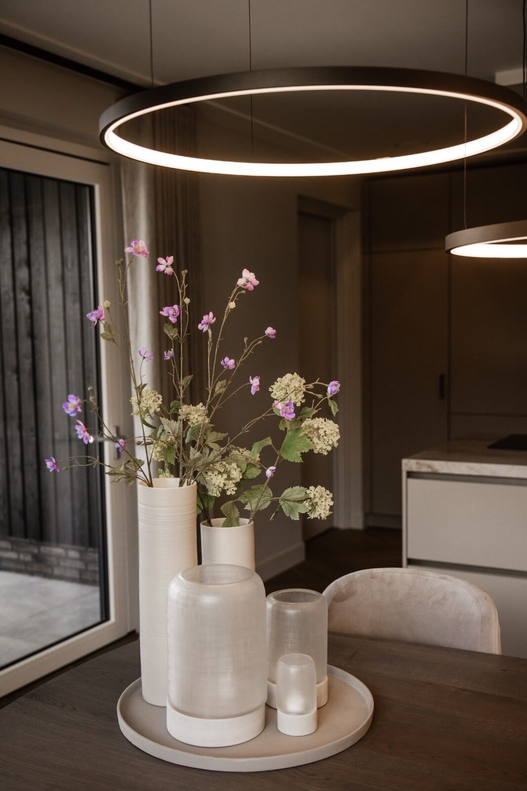 Hoge vazen met zijden bloesem en veldbloemen op een eettafel
